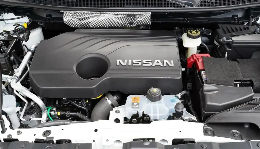 Silnik Nissana Qashqai J11, z widocznym napisem NISSAN na czarnej osłonie. Widać akumulator i zbiornik płynu chłodniczego.