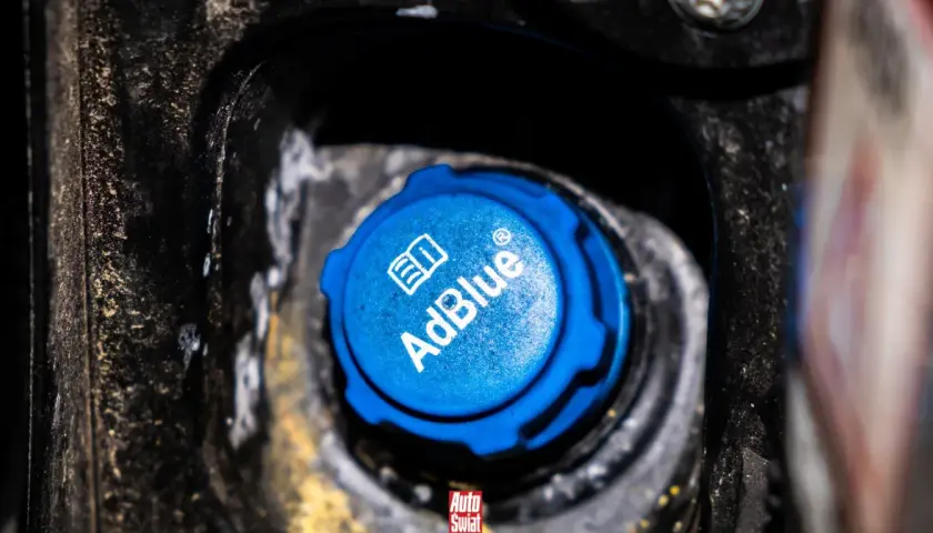 Niebieski korek wlewu AdBlue w samochodzie, z widocznym logo i napisem.