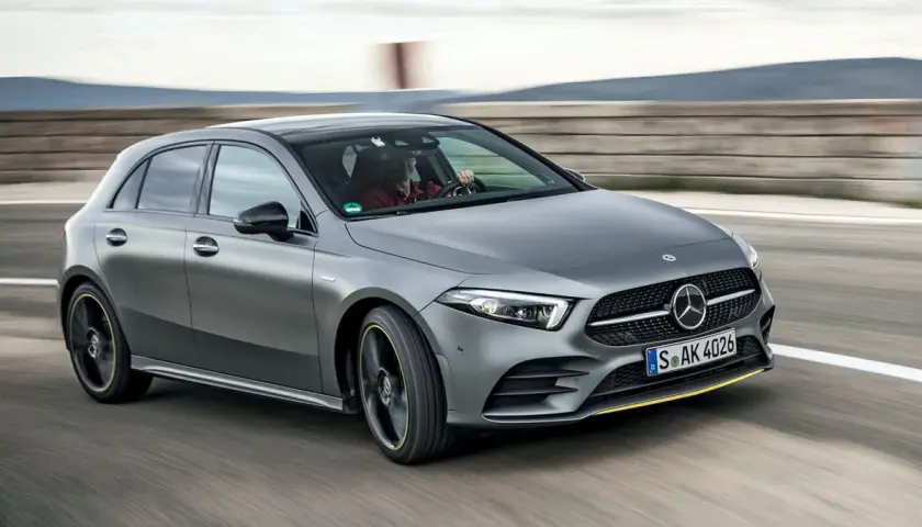 Szary Mercedes W177 pędzi po torze, kierowca w czerwonej koszuli pewnie trzyma kierownicę.