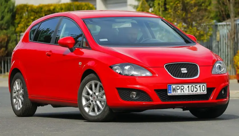 Czerwony Seat Leon 1P1 z polskimi tablicami rejestracyjnymi WPR 10510 na drodze, z kierowcą za kierownicą.