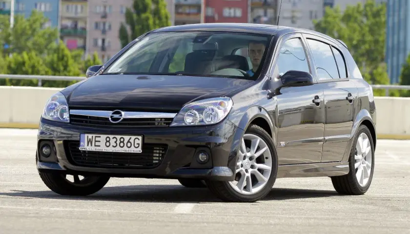 Czarny Opel Astra H na parkingu. Kierowca zastanawia się, jakie żarówki wybrać do swojego auta.