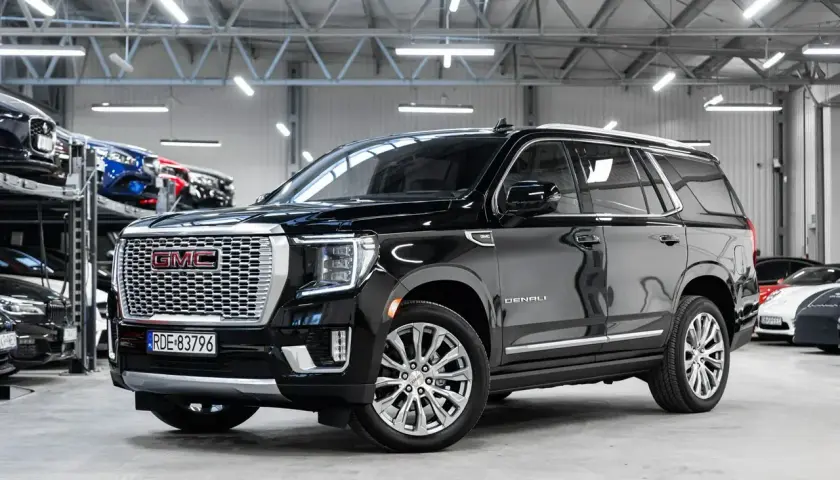 Czarny GMC Yukon Denali lśni w salonie samochodowym, gotowy na przygodę.