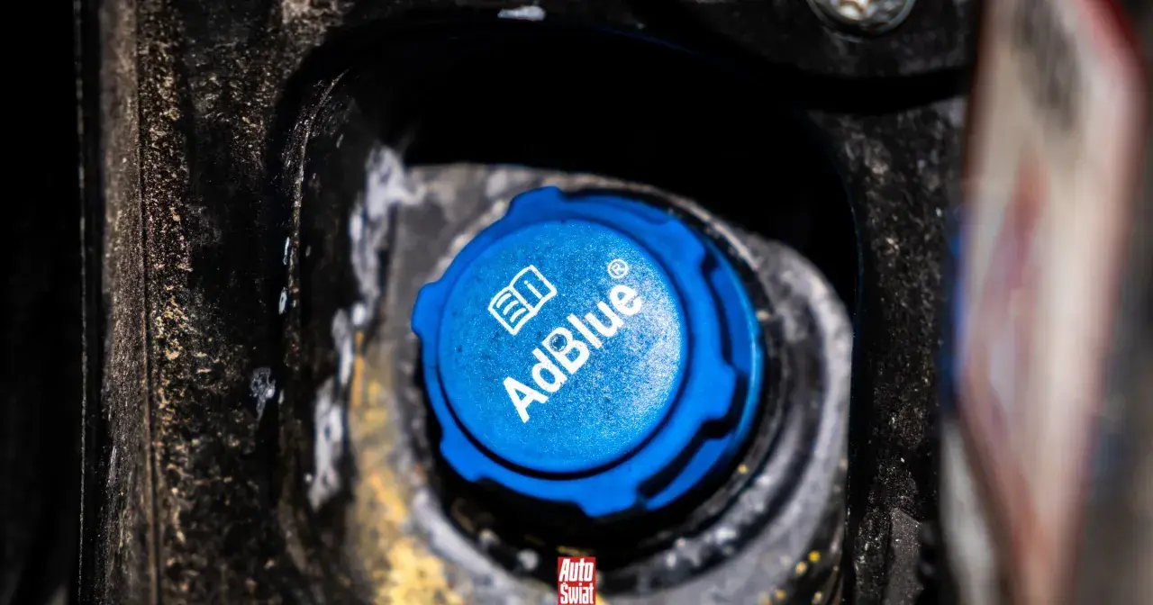 Niebieski korek wlewu AdBlue w samochodzie, z widocznym logo i napisem.