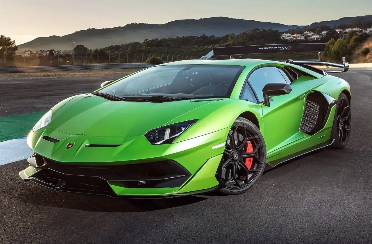 Jaskrawozielony Lamborghini Aventador SVJ na torze wyścigowym, z górami w tle.