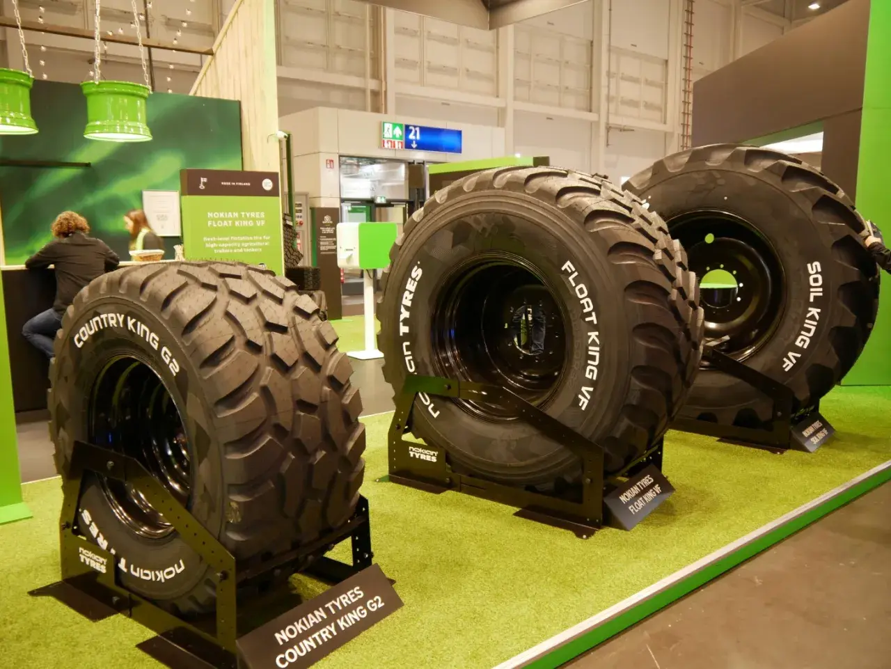 Trzy duże opony rolnicze Nokian Tyres na zielonej wykładzinie.