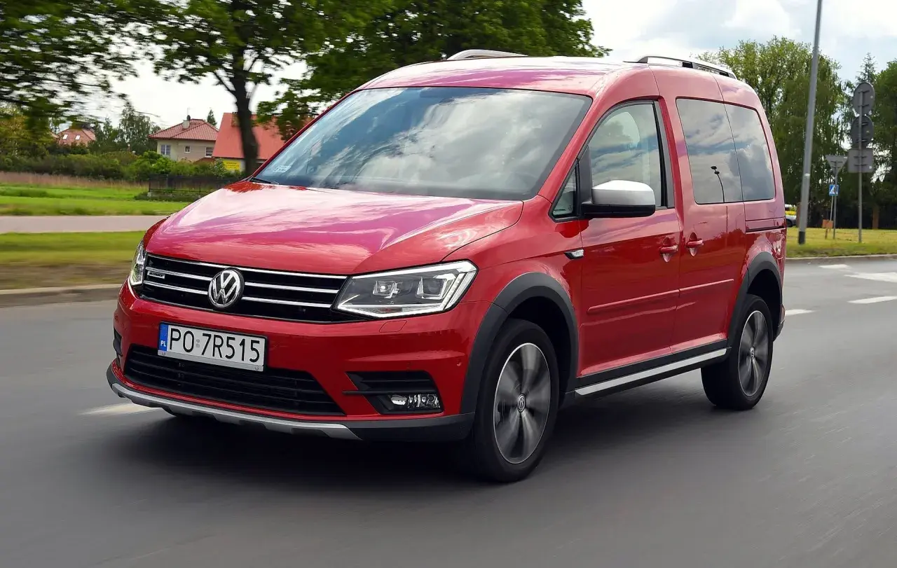 Czerwony Volkswagen Caddy 3 w ruchu, z widocznymi felgami i terenowym wyglądem.