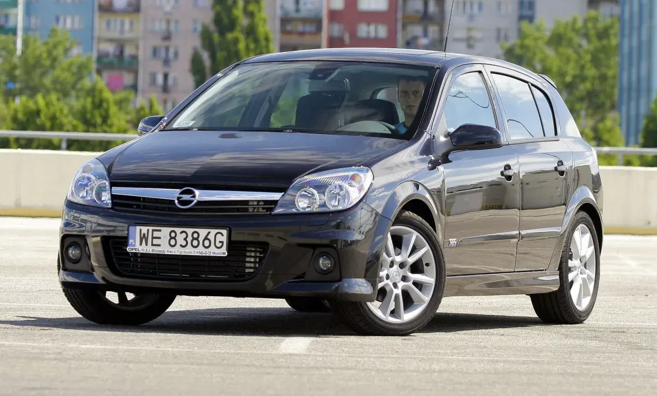 Czarny Opel Astra H na parkingu. Kierowca zastanawia się, jakie żarówki wybrać do swojego auta.