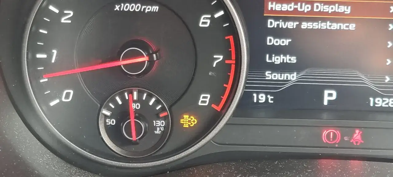 Na desce rozdzielczej Kia Sportage świeci się kontrolka wypalania DPF. Obok wskaźnik temperatury i obrotomierz.