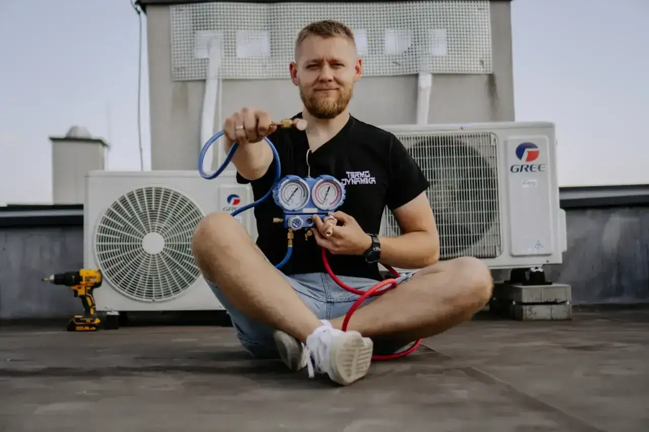 Technik z manometrem sprawdza klimatyzację. Objawy za mało czynnika w klimatyzacji domowej mogą być widoczne na wskaźnikach.