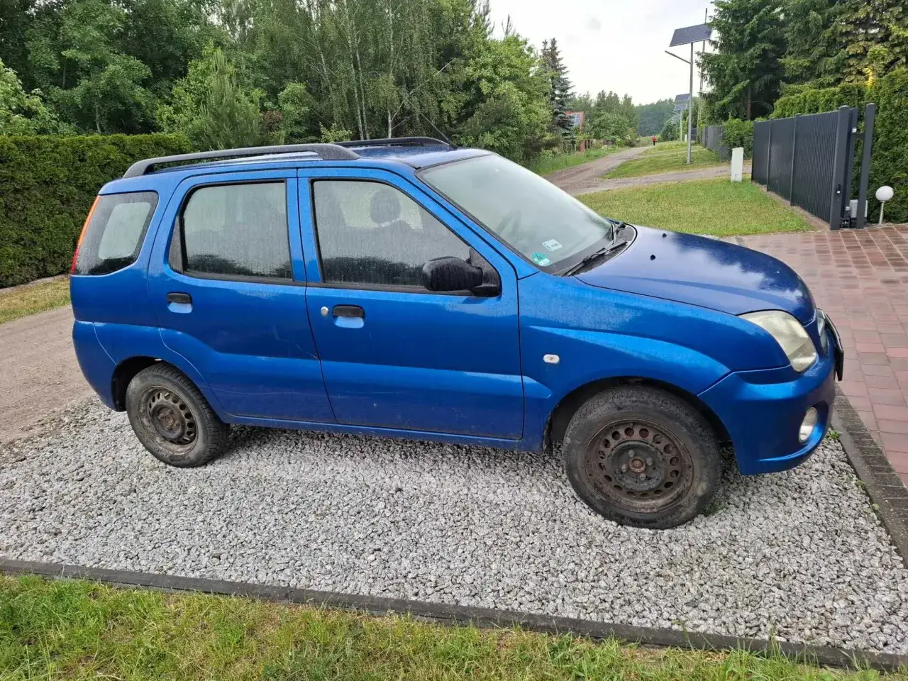 Niebieski Subaru Justy G3X stoi na żwirowej podjazd.