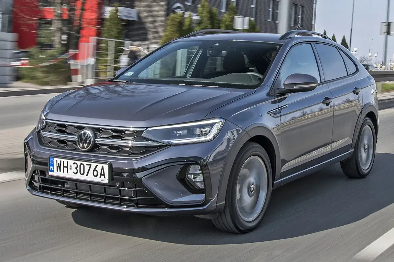 Szary Volkswagen Taigo pędzi po drodze, błyszcząc w słońcu.