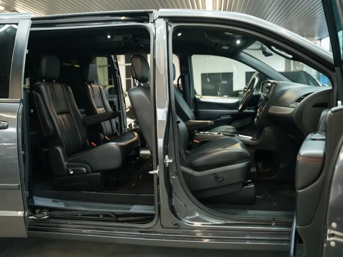 Wnętrze luksusowego minivana Hyundai Entourage z czarnymi skórzanymi fotelami i czerwonymi przeszyciami.