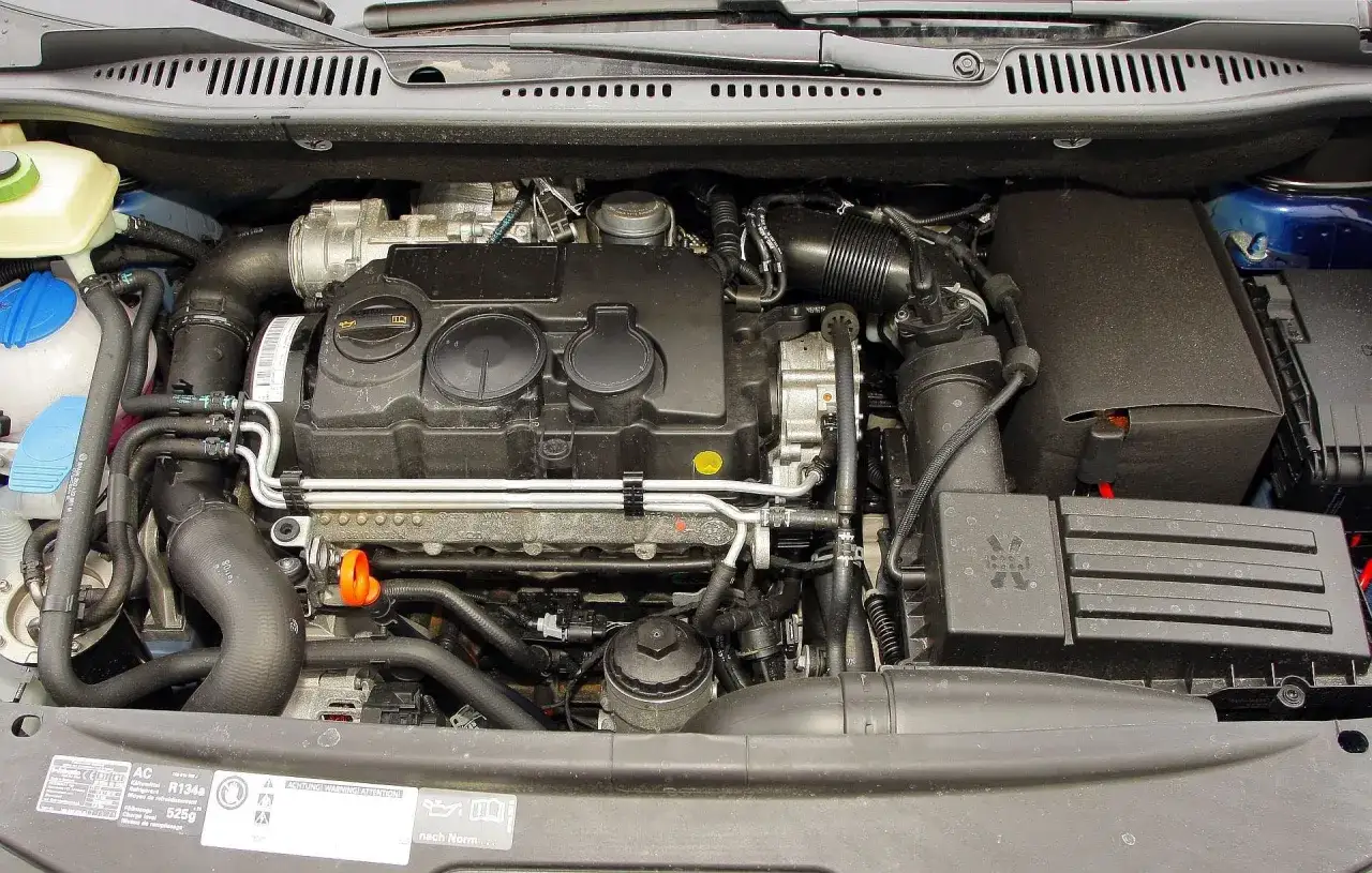 Silnik Volkswagena Caddy 3. Widoczne elementy układu dolotowego, chłodzenia i osłony silnika.