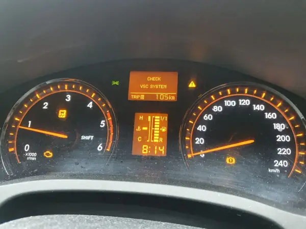 Kontrolki na desce rozdzielczej Toyota T27: CHECK VSC SYSTEM, kontrolka silnika, kontrolka ESP i hamulca. Przebieg 10.5 km.