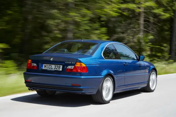 Niebieskie BMW E46 328 Ci z roku produkcji 2000, jadące po leśnej drodze.
